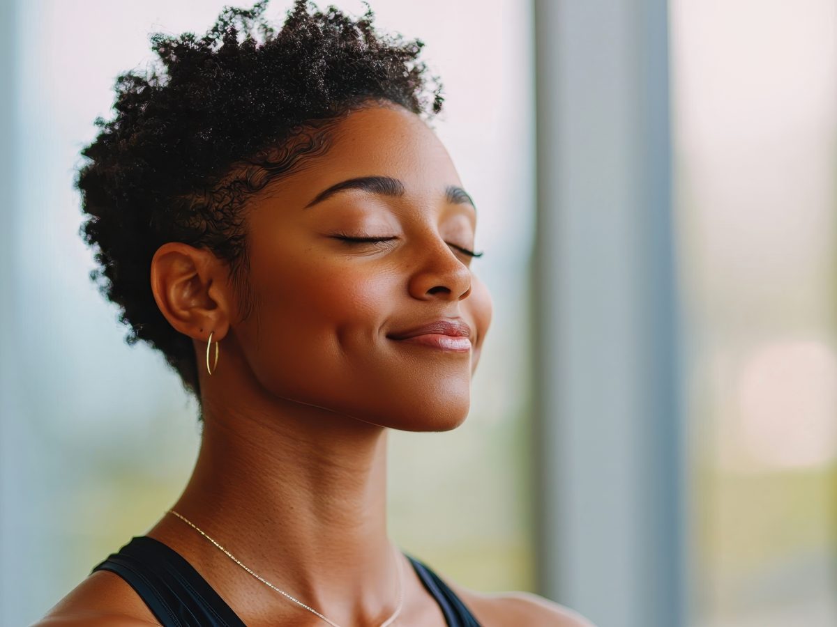 Mindful meditation practice by a smiling woman in workout clothes indoor studio setting
