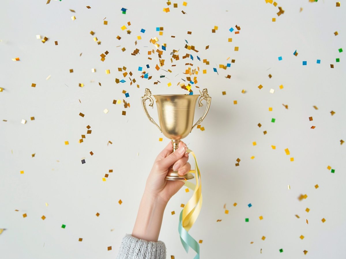 AI Generated hands of businesswoman holding and lift a golden trophy, surrounding with congratulations confetti ribbon flakes in white background.